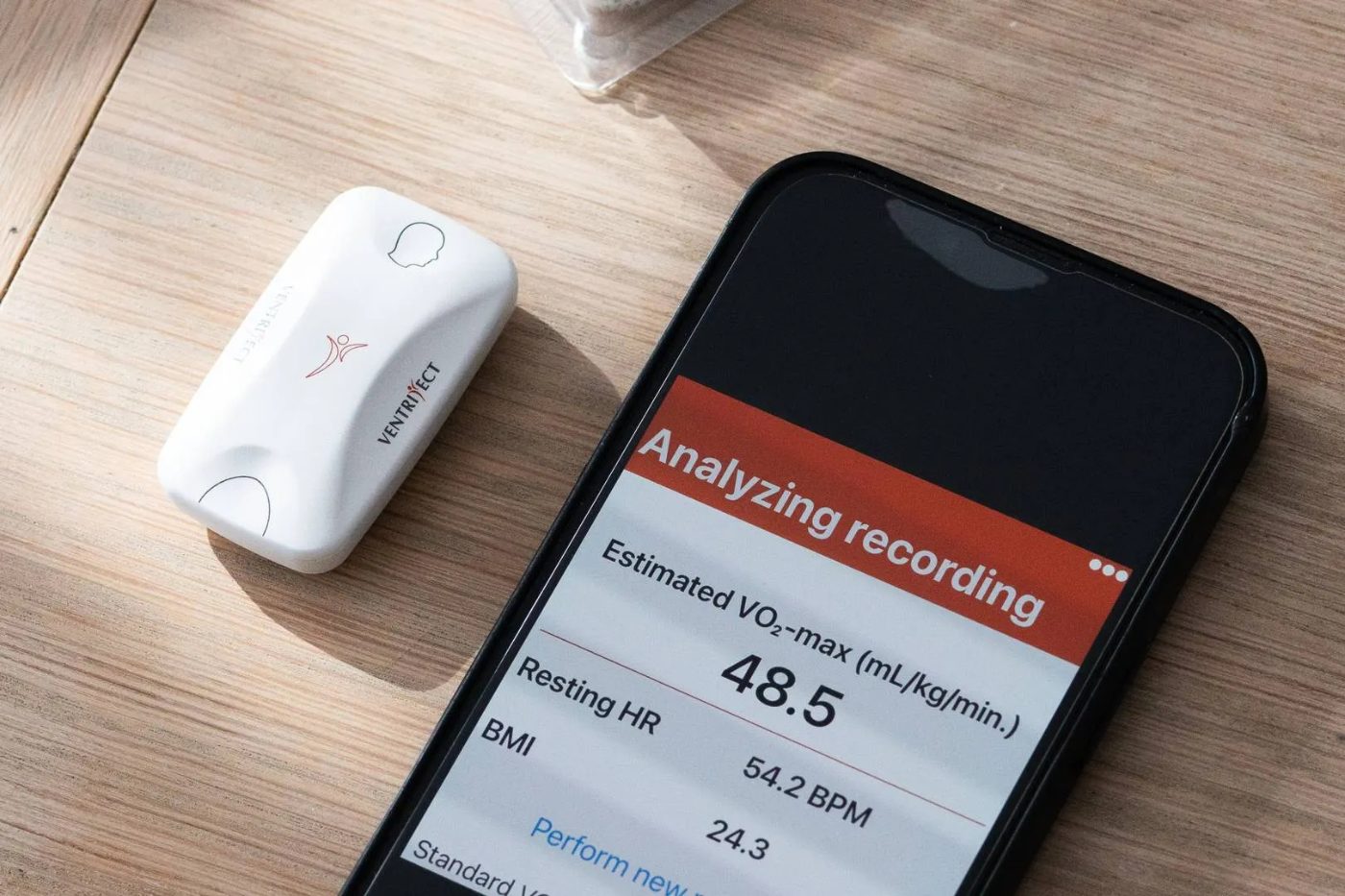 A VentriJect sensor beside a phone showing an estimated VO₂-max reading